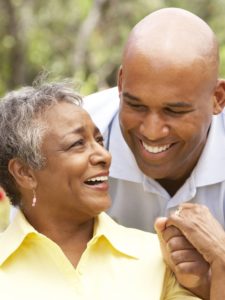 Senior Woman Being Hugged By Adult Son In Garden